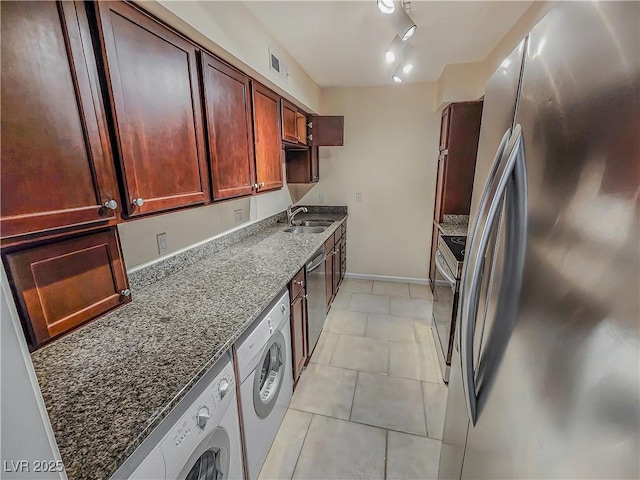 kitchen featuring dark stone counters, track lighting, sink, appliances with stainless steel finishes, and light tile patterned flooring