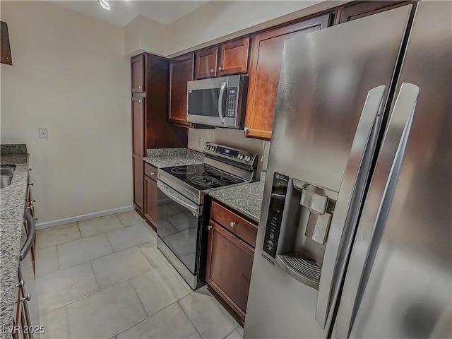 kitchen featuring light tile patterned floors, stainless steel appliances, and dark stone counters