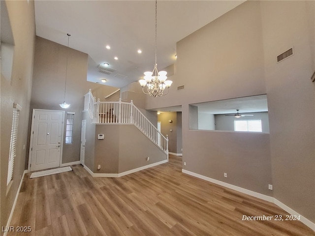 interior space featuring hardwood / wood-style floors, a towering ceiling, and ceiling fan with notable chandelier