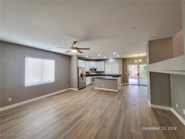 unfurnished living room featuring ceiling fan with notable chandelier, light hardwood / wood-style floors, and sink