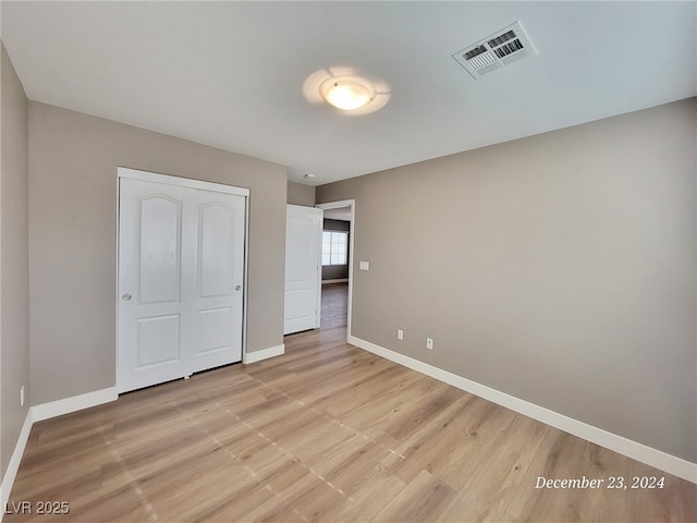 unfurnished bedroom with light hardwood / wood-style flooring and a closet