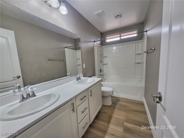 full bathroom with hardwood / wood-style floors, vanity, bathing tub / shower combination, toilet, and a textured ceiling