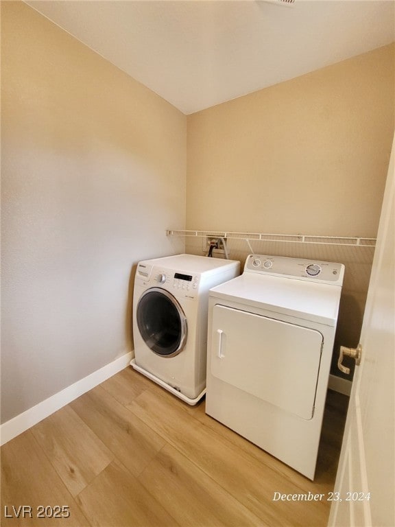 washroom featuring washing machine and dryer and light hardwood / wood-style flooring