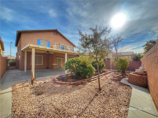 rear view of property featuring ceiling fan and a patio area