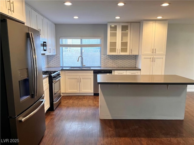 kitchen featuring a breakfast bar, sink, appliances with stainless steel finishes, a kitchen island, and white cabinetry