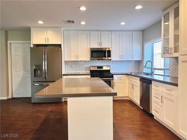 kitchen with a center island, dark wood-type flooring, white cabinets, sink, and appliances with stainless steel finishes