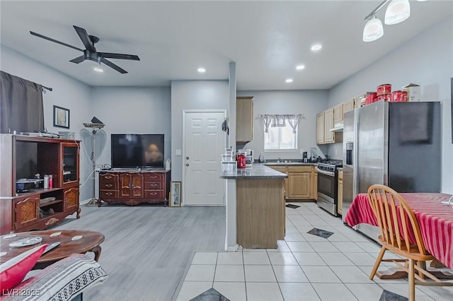 kitchen featuring ceiling fan, stainless steel appliances, kitchen peninsula, pendant lighting, and light brown cabinetry