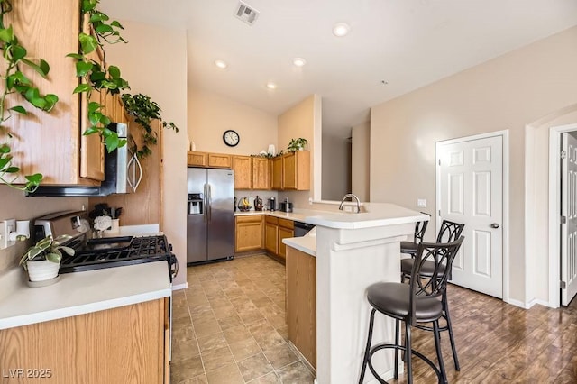 kitchen with kitchen peninsula, a high ceiling, a breakfast bar, range with gas cooktop, and stainless steel fridge with ice dispenser