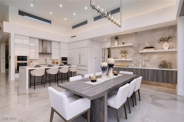 dining space with a high ceiling, an inviting chandelier, and sink