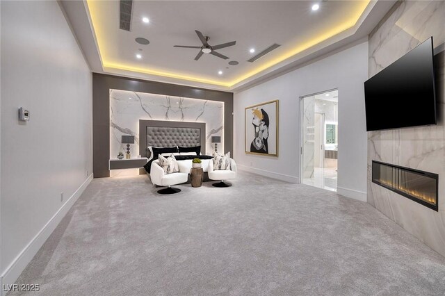 interior space with a tray ceiling, ensuite bath, and a fireplace