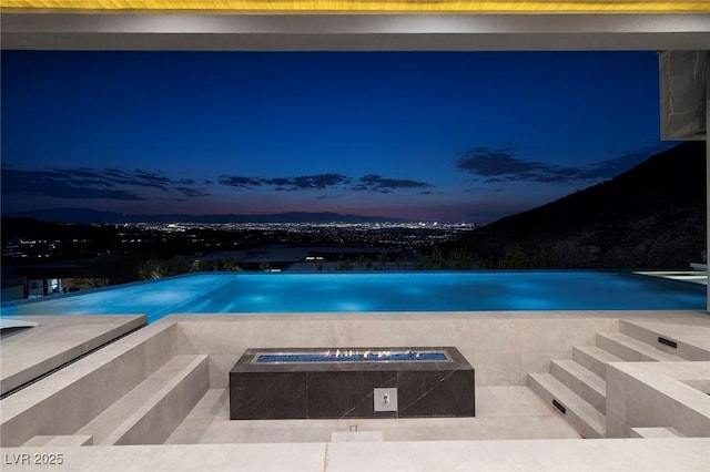 pool at dusk featuring an outdoor fire pit