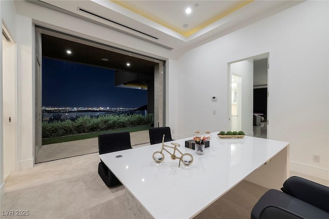 interior space with a raised ceiling, a kitchen bar, and light carpet