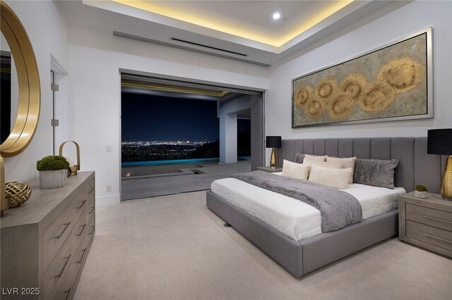 bedroom with a raised ceiling and light carpet