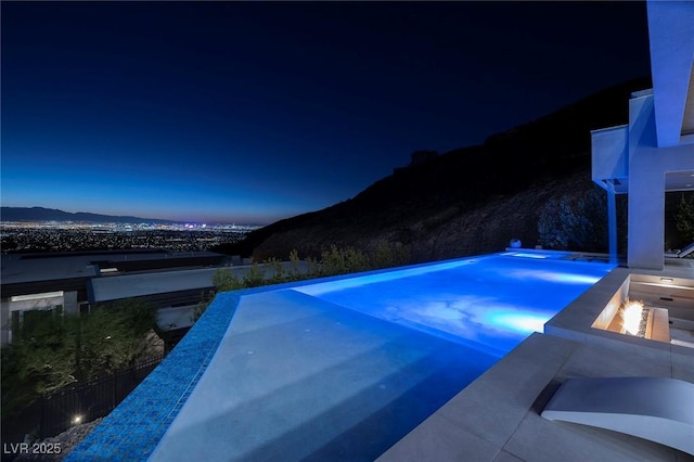 view of swimming pool with a mountain view and a fire pit