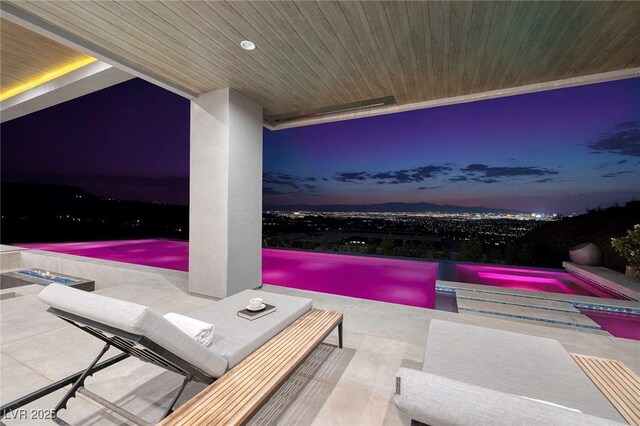 patio terrace at dusk with a swimming pool with hot tub