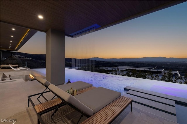 snow covered patio featuring a fire pit and a mountain view