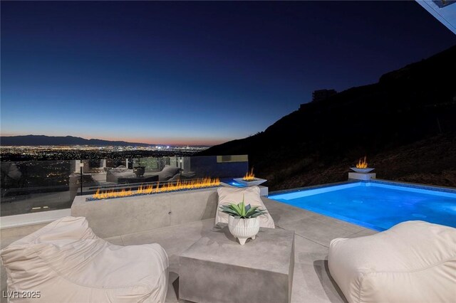 pool at dusk featuring a mountain view and a patio