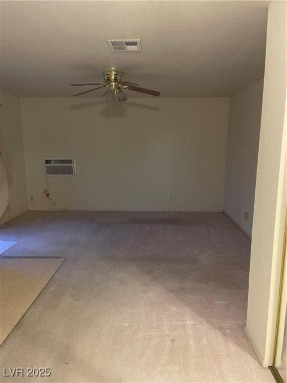 carpeted spare room featuring a wall mounted AC and ceiling fan