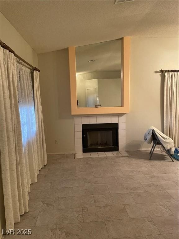 unfurnished living room featuring a tile fireplace and a textured ceiling