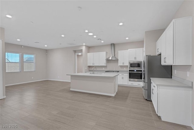 kitchen featuring a center island with sink, white cabinets, sink, wall chimney exhaust hood, and appliances with stainless steel finishes