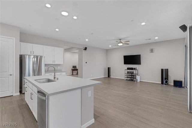 kitchen featuring appliances with stainless steel finishes, ceiling fan, sink, a center island with sink, and white cabinetry