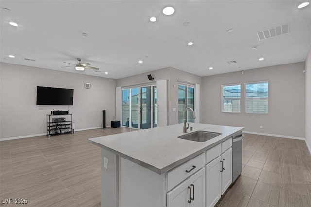 kitchen with ceiling fan, sink, dishwasher, white cabinets, and an island with sink