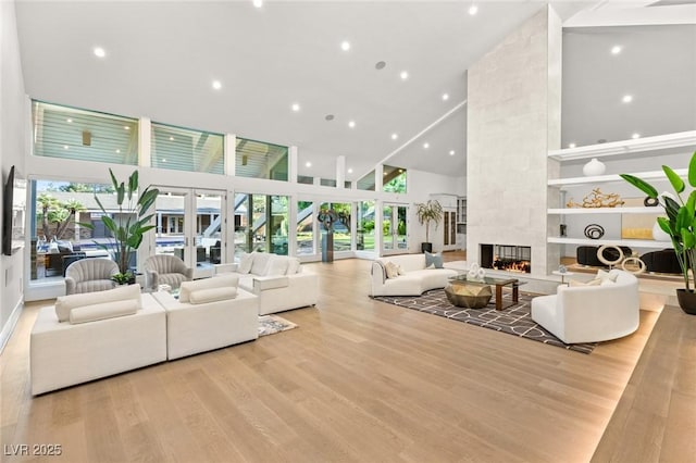 living room featuring a fireplace, high vaulted ceiling, and light wood-type flooring