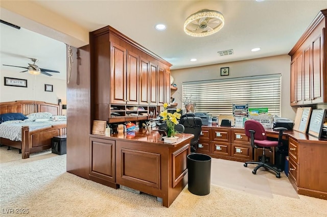 home office with light carpet, built in desk, and ceiling fan