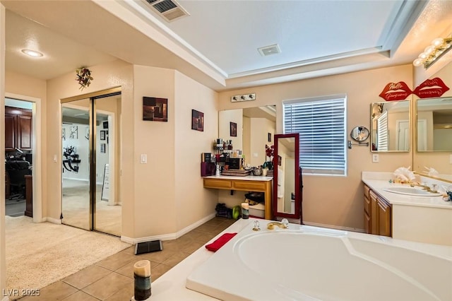 bathroom featuring tile patterned flooring, vanity, a raised ceiling, and a bath