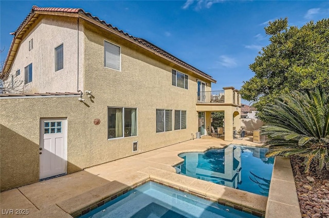 rear view of property with a patio area, a hot tub, and a balcony