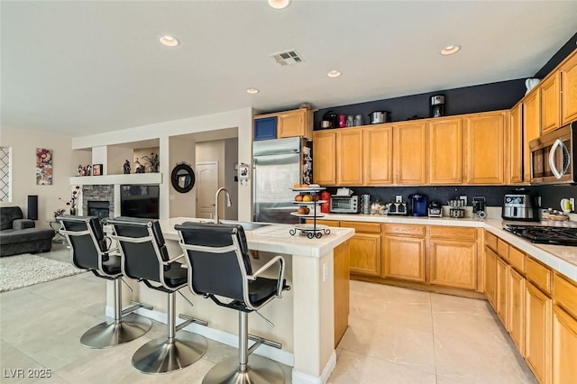 kitchen featuring a breakfast bar, tasteful backsplash, sink, stainless steel appliances, and a center island with sink