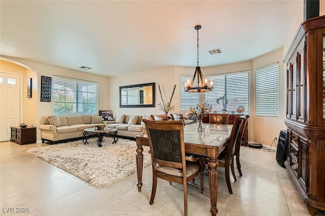 tiled dining space featuring a healthy amount of sunlight and a notable chandelier