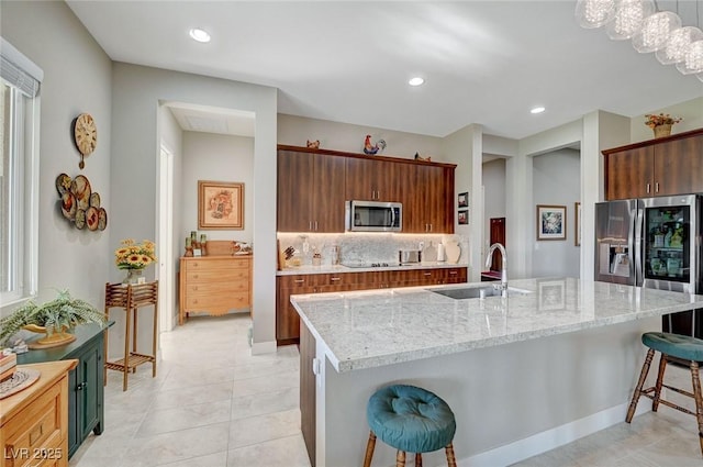 kitchen featuring stainless steel appliances, a kitchen island with sink, pendant lighting, a kitchen bar, and decorative backsplash