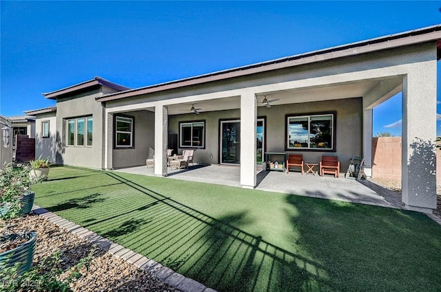 back of property with ceiling fan, a patio area, and a yard