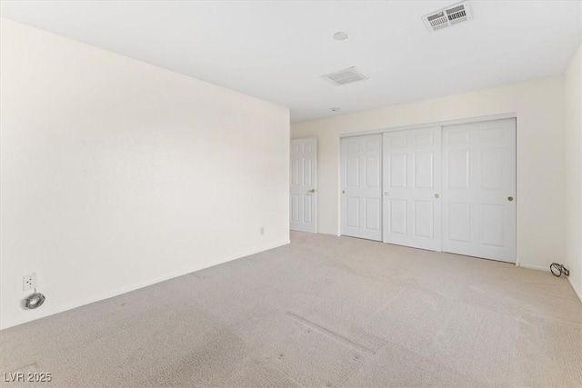 unfurnished bedroom with light carpet and a closet