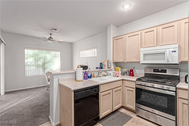 kitchen featuring sink, kitchen peninsula, black dishwasher, and stainless steel gas range