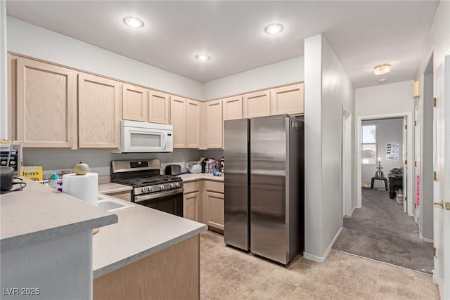 kitchen featuring kitchen peninsula, appliances with stainless steel finishes, light brown cabinets, and light carpet