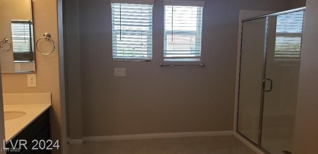 bathroom with a shower with door, vanity, and a healthy amount of sunlight