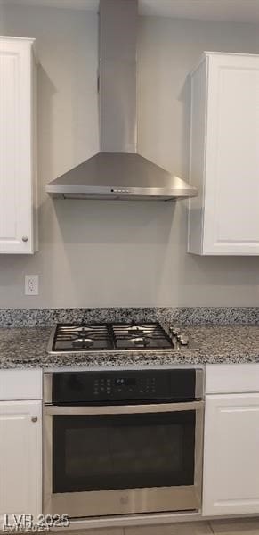 kitchen with white cabinets, dark stone countertops, wall chimney exhaust hood, and stainless steel appliances