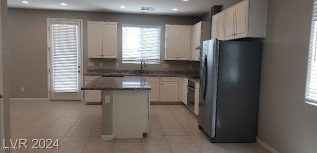 kitchen featuring stainless steel appliances, sink, white cabinetry, a kitchen island, and light tile patterned flooring