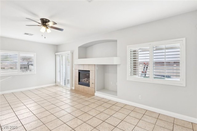 unfurnished living room featuring a fireplace, ceiling fan, and light tile patterned flooring