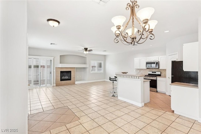 kitchen featuring white cabinets, ceiling fan with notable chandelier, light tile patterned floors, and appliances with stainless steel finishes