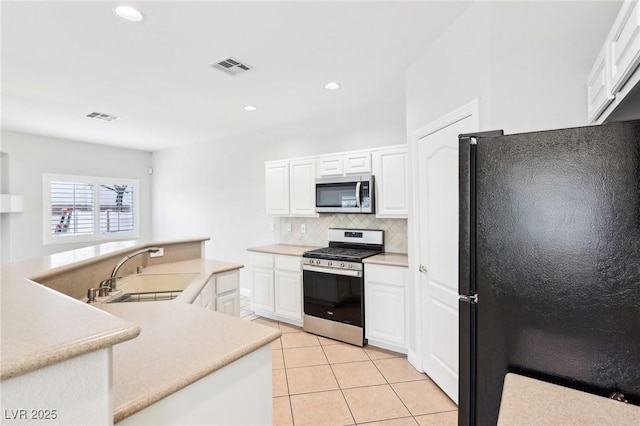 kitchen featuring tasteful backsplash, stainless steel appliances, sink, light tile patterned floors, and white cabinets