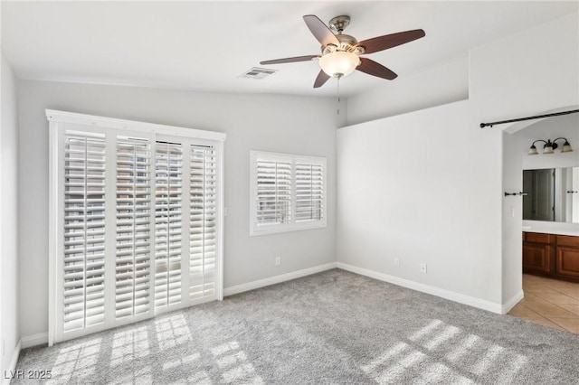 empty room with ceiling fan, light colored carpet, and vaulted ceiling