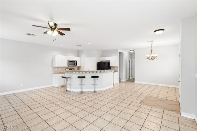 kitchen with a center island, white cabinets, ceiling fan with notable chandelier, light tile patterned floors, and a breakfast bar area