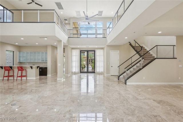 interior space featuring french doors, ceiling fan, and a high ceiling