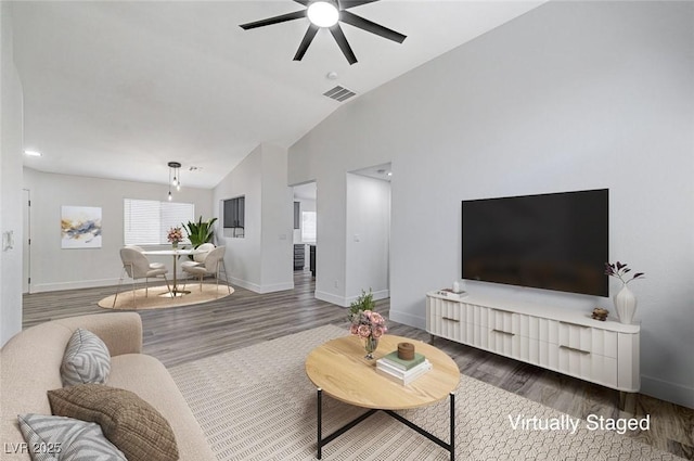 living room with ceiling fan, dark hardwood / wood-style floors, and vaulted ceiling