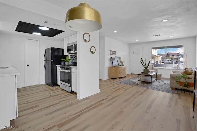 kitchen with decorative light fixtures, a textured ceiling, light hardwood / wood-style flooring, stainless steel appliances, and white cabinets