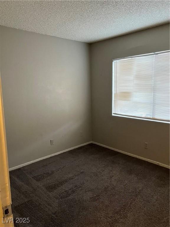 spare room with dark carpet and a textured ceiling