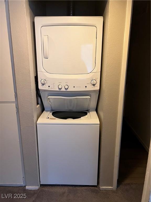 clothes washing area with dark carpet and stacked washing maching and dryer